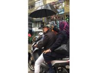 Yağmurda kendisi ıslanma pahasına kocasını şemsiyeyle korudu